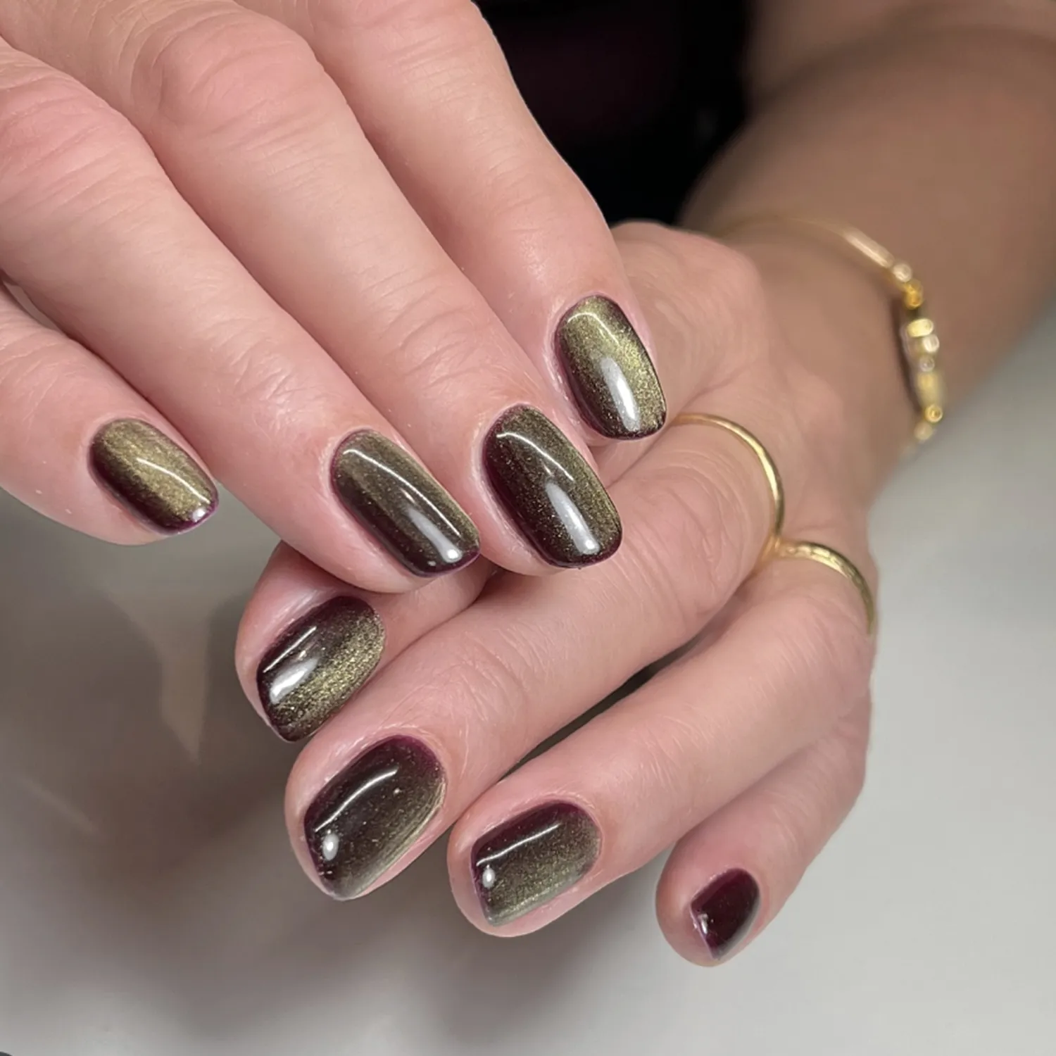 A pair of hands showcasing polished nails with a gradient pattern