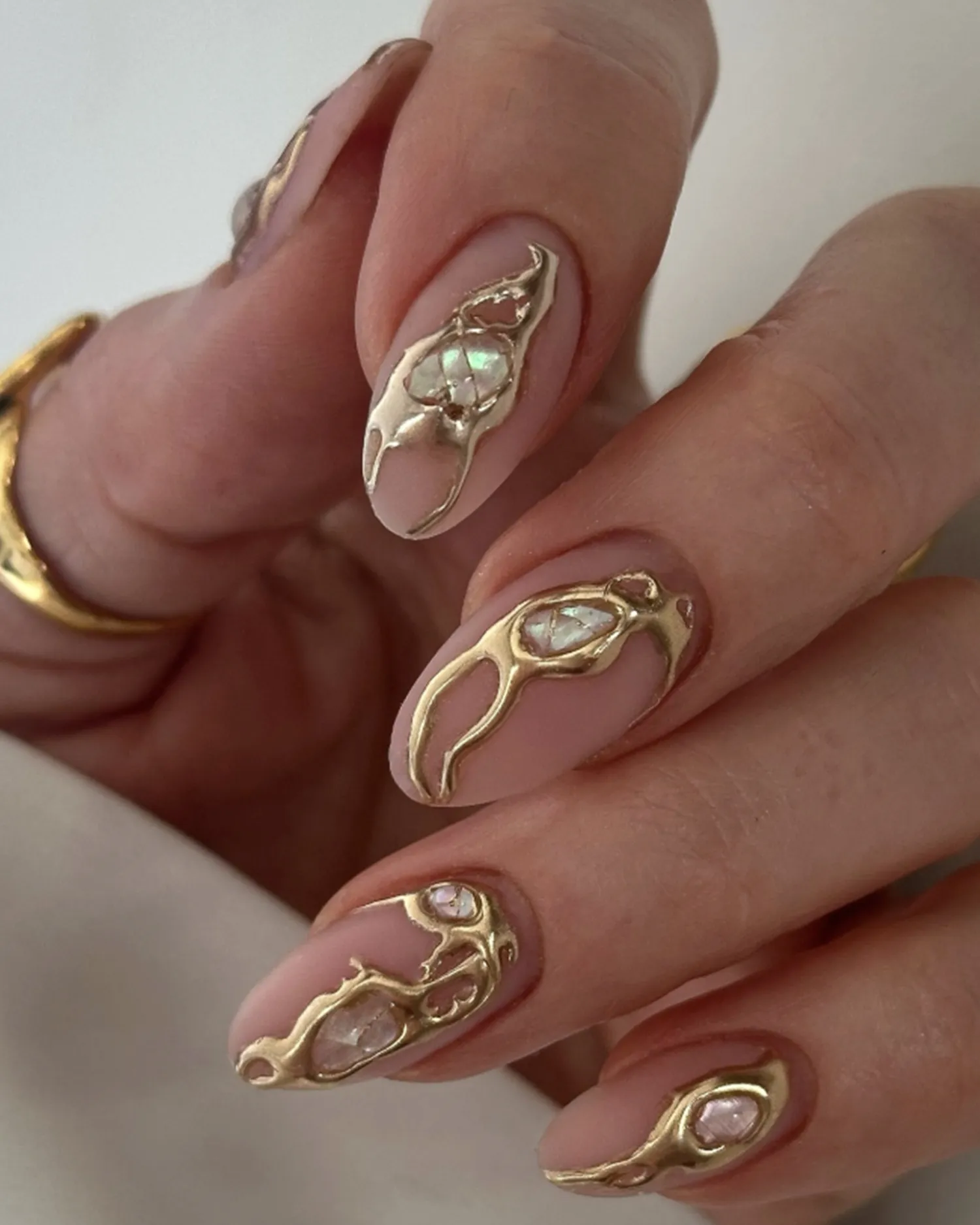 A closeup of hands with decorative nail art featuring golden accents and intricate designs