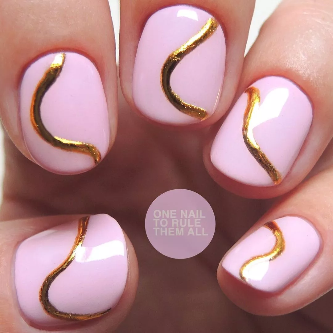 Manicure design with golden wavy lines on a light pink base