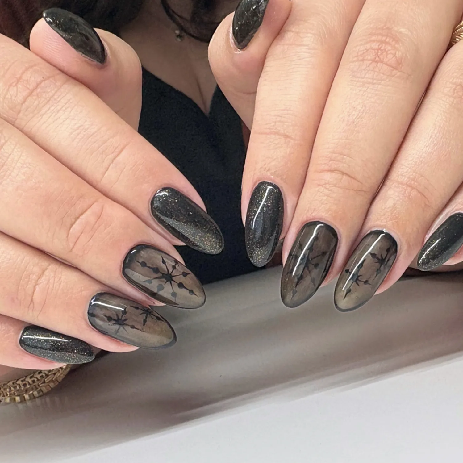 Hands displaying manicured nails with intricate designs on a smooth surface