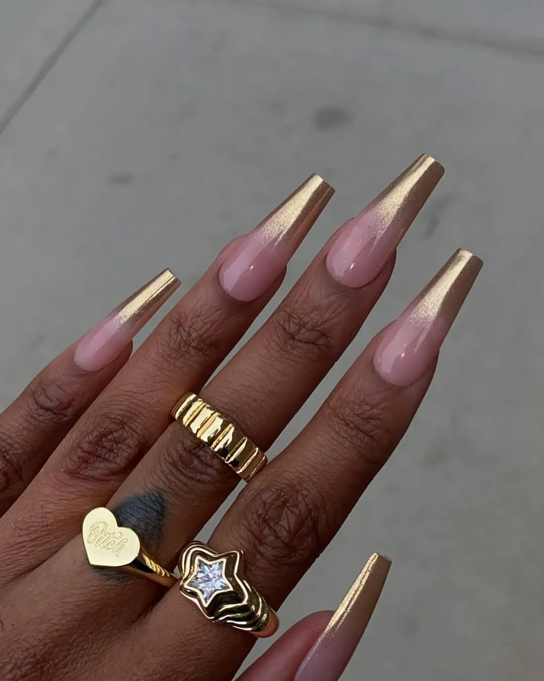 A hand with long manicured nails and gold rings