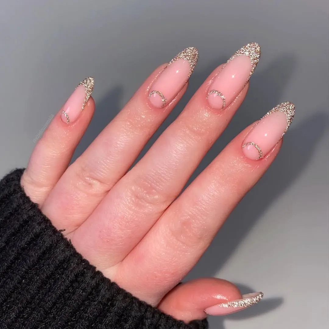 Nude nails with sparkly gold French tips and half-moon accents