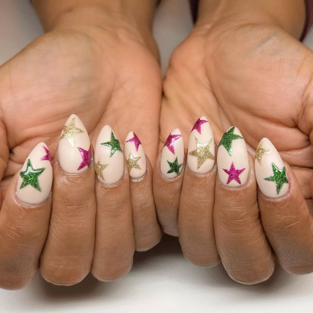 cream based manicure with green, gold, and pink stars