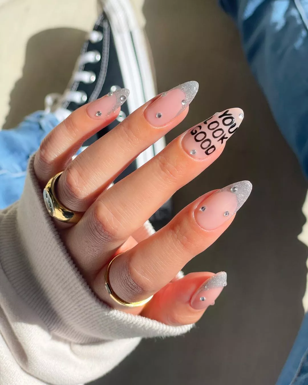 Manicured hand displaying nails with decorative designs one nail has the text You look good written on it