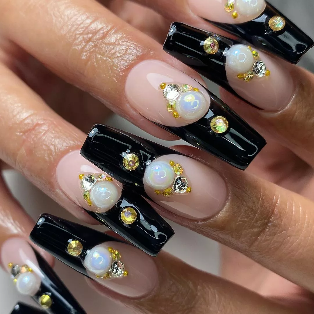 Closeup of hands with black French tips and decorative gem nails