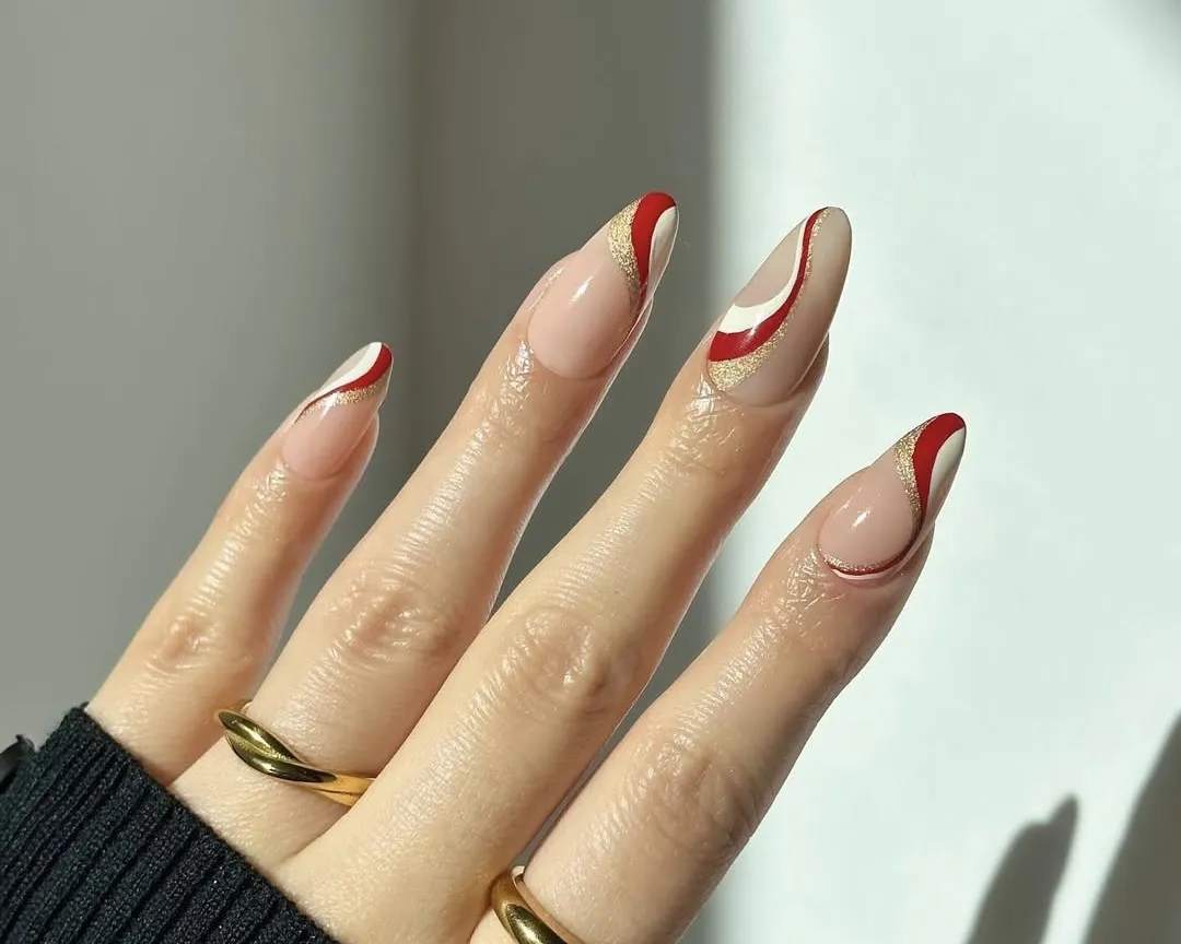 Candy cane nails with white, red, and gold glitter swirls.