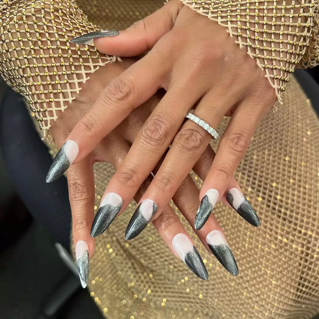 Person with long, almond-shaped nails that have a milky white base and glittery black tips