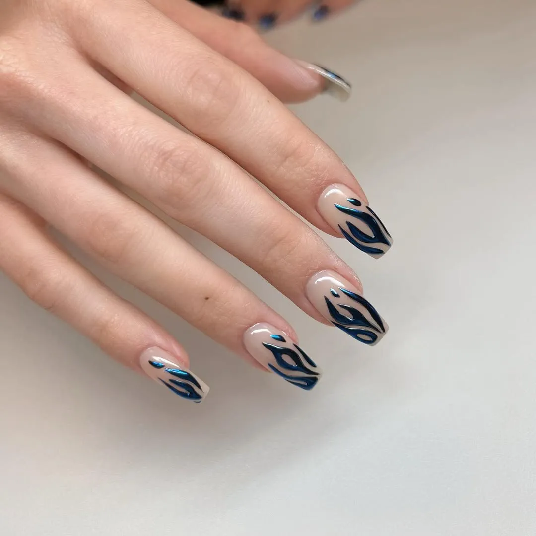 Person shows off their medium-length, square-shaped nails with blue chrome flames on each