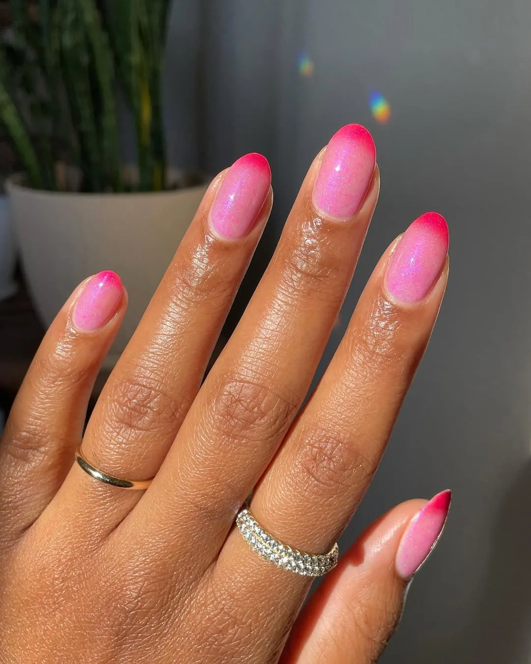 Person with pink French tip nails, which have hot pink tips and a light, sparkly pink base