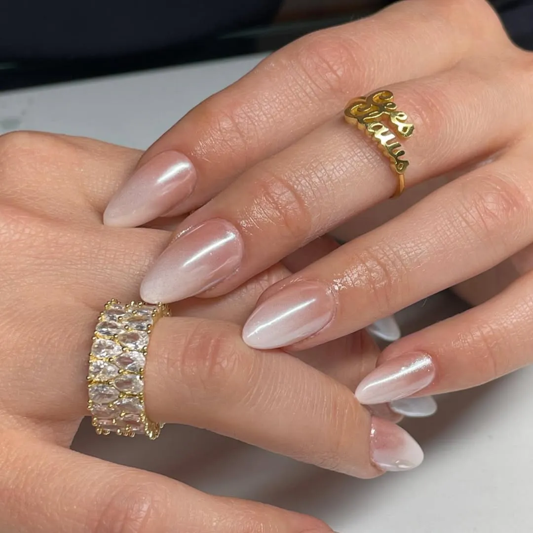 Manicured hands wearing ornate gold rings with gemstones and text details