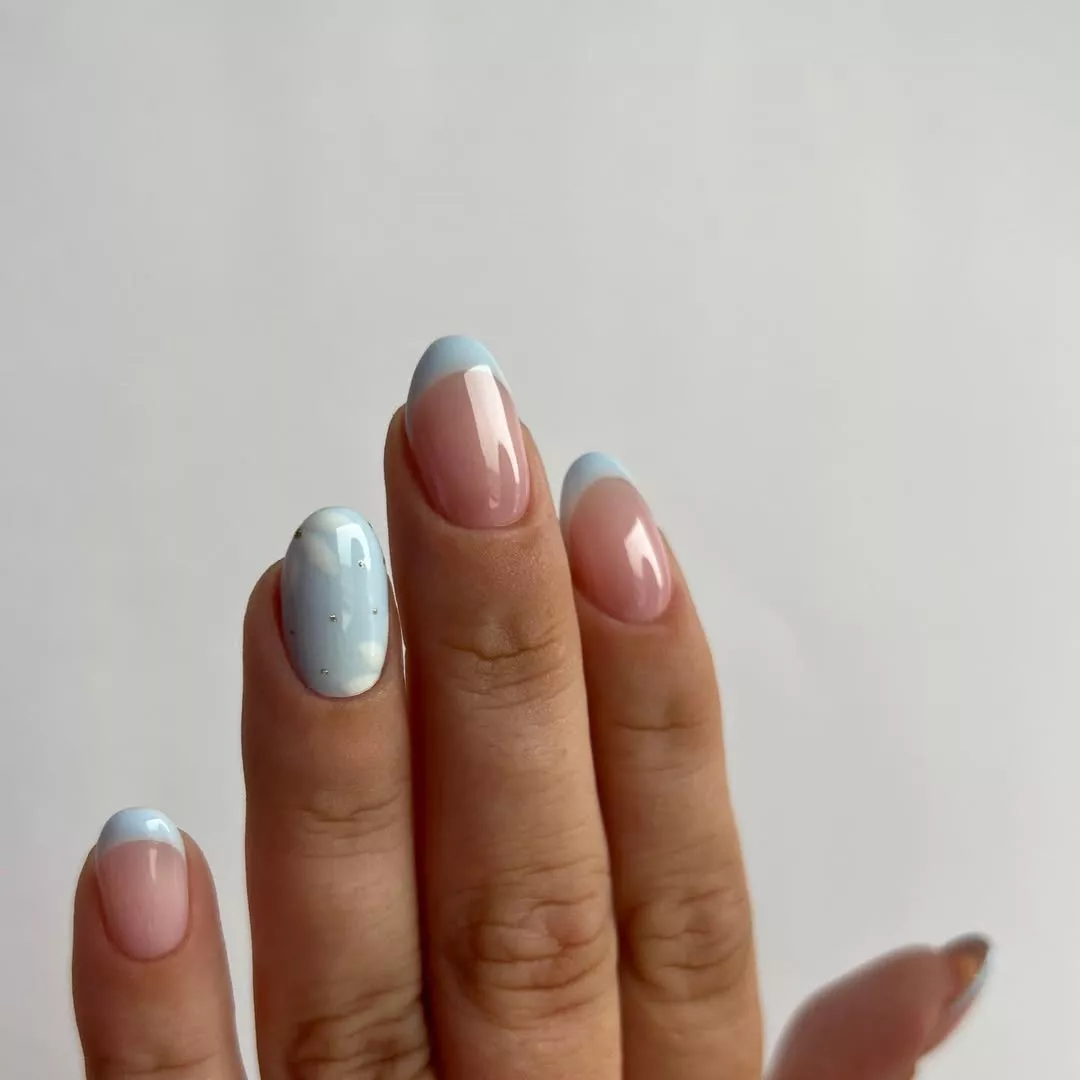 Light blue chrome nails with cloud design accents and French tips