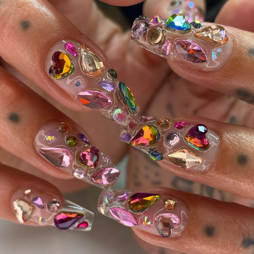 Person with clear, coffin-shaped nails and colorful '90s gems on each