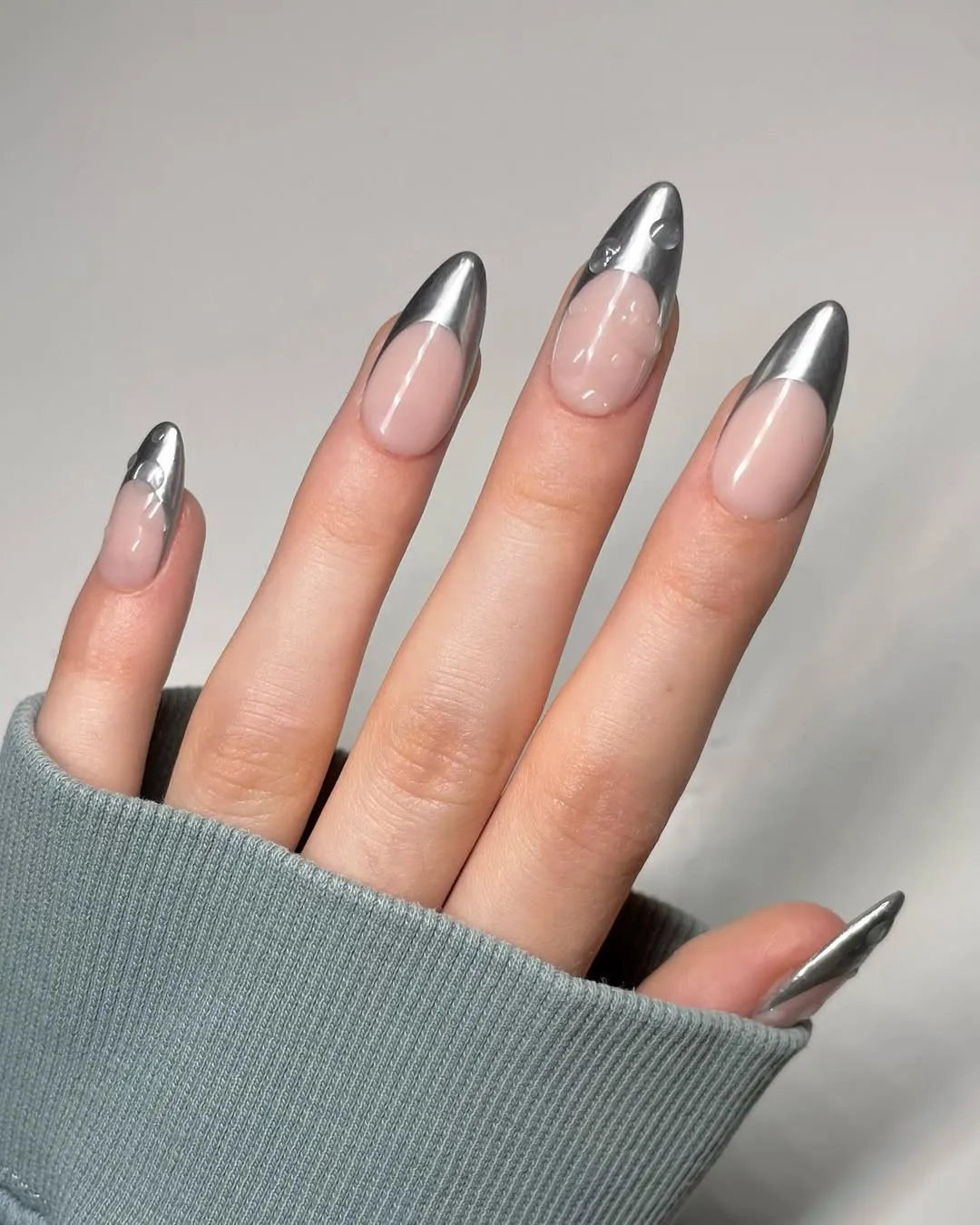 Hand with metallic nail art featuring silver tips