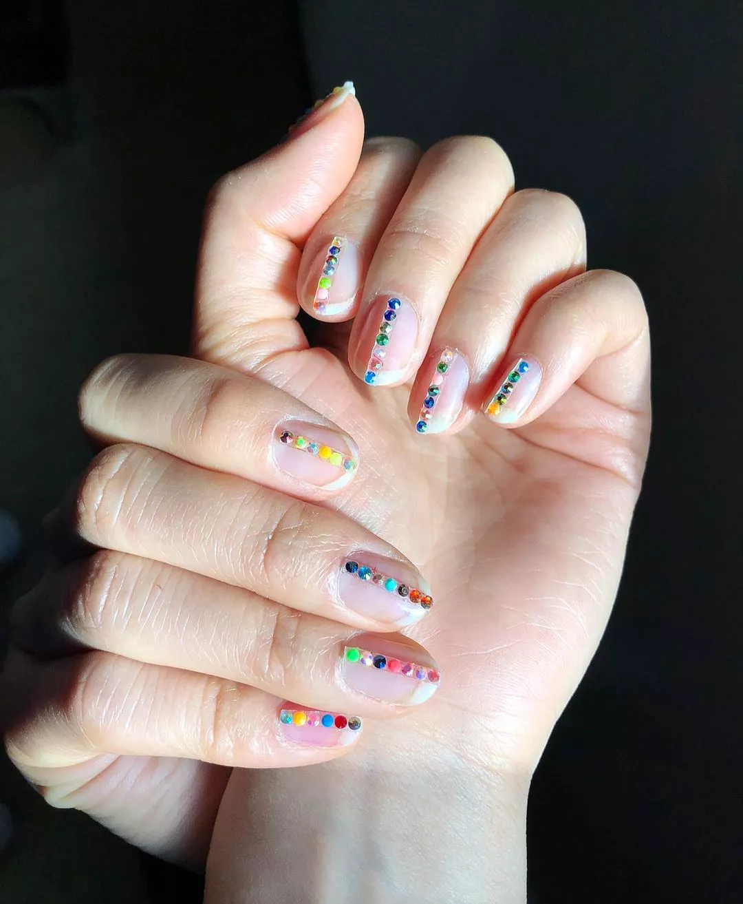 Person with clear nails that have a line of gems straight down the middle of each nail