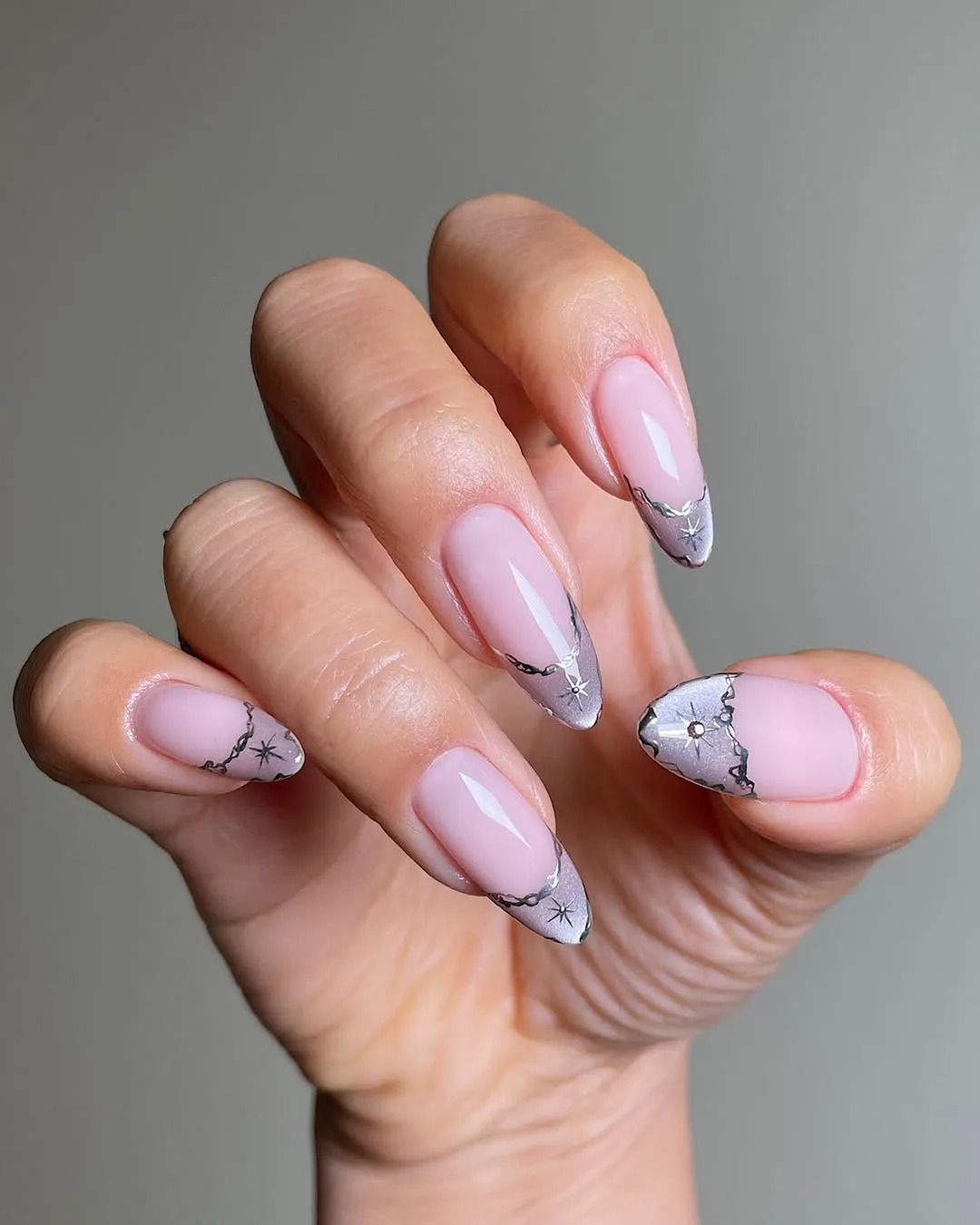 A hand displaying manicured nails with a unique decorated design on the tips