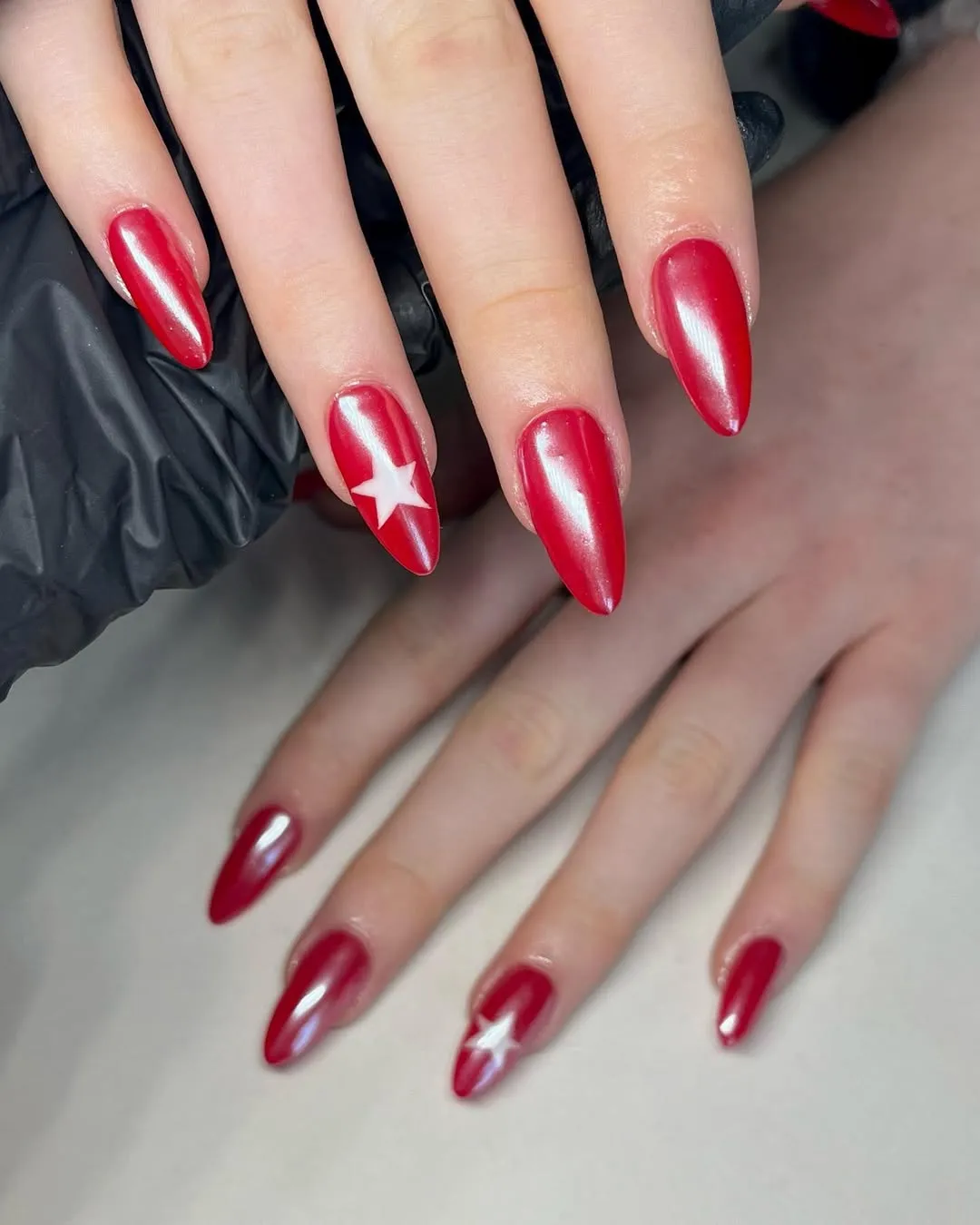 Hands with redpainted nails featuring a star accent on one nail