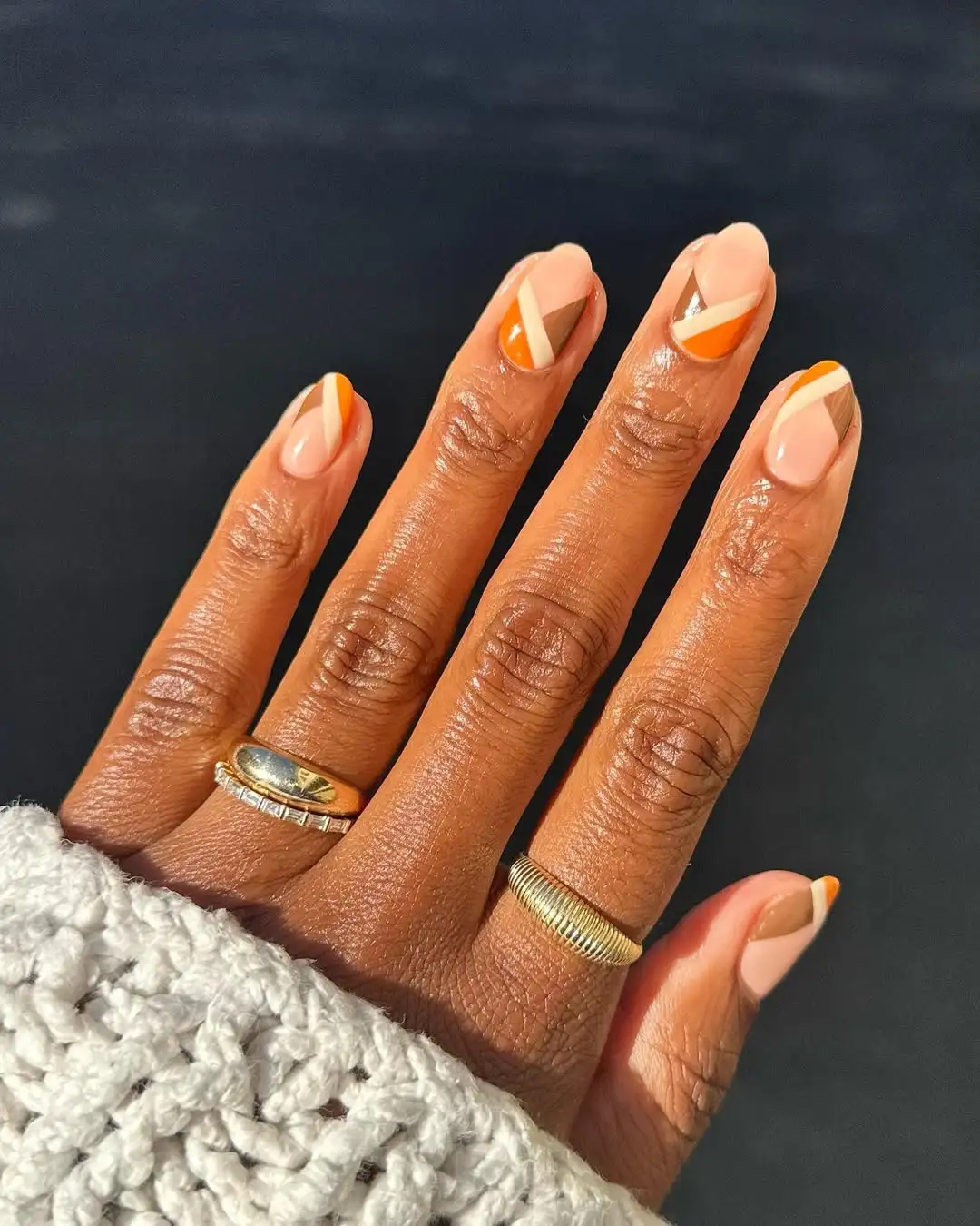 Person with short, oval-shaped nails that have a brown, braid-like pattern at the tips and base