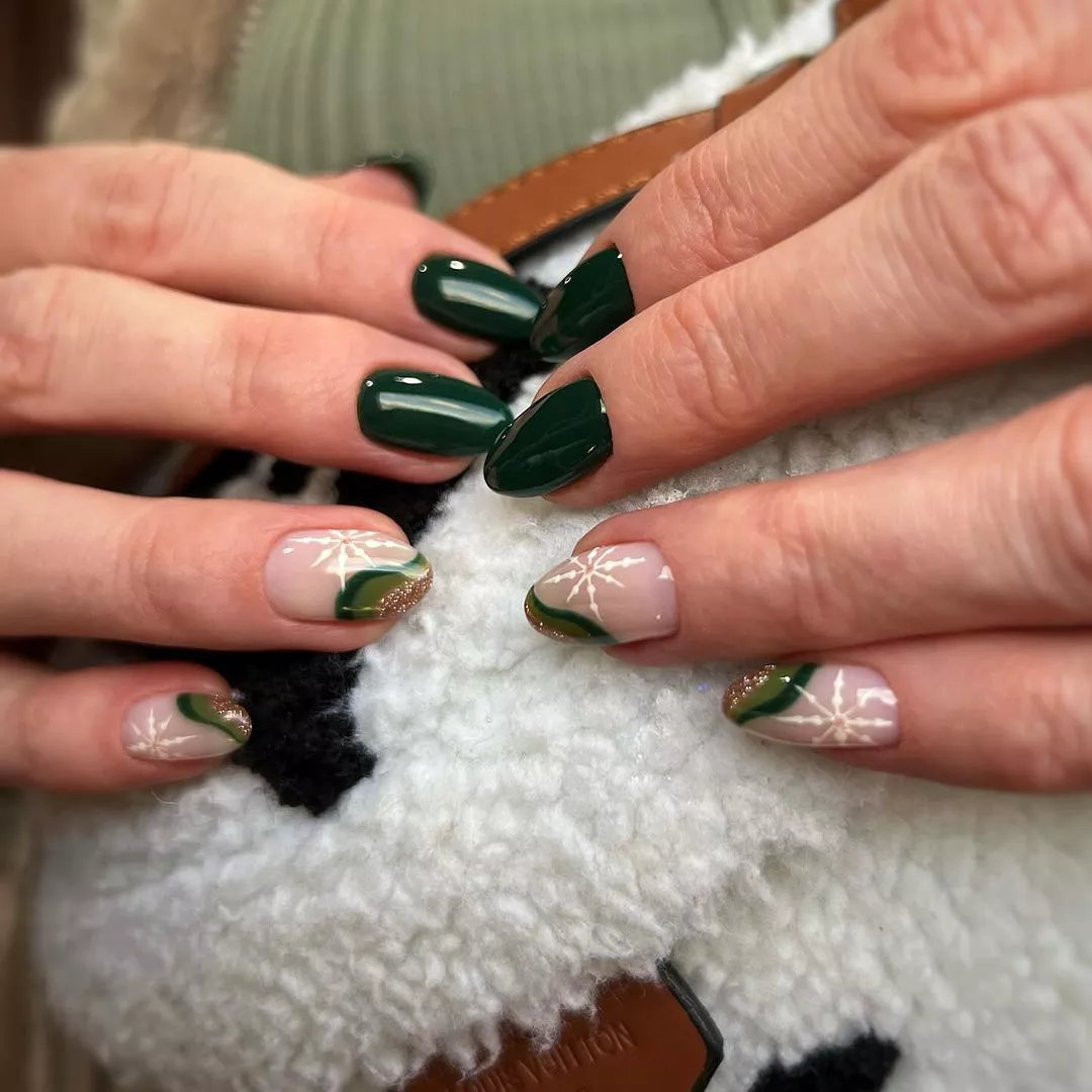 A dark green manicure with swirls and snowflakes for winter.