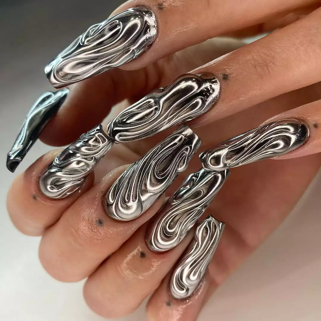 Person sporting long, 3D metallic nails in a silver coffin shape