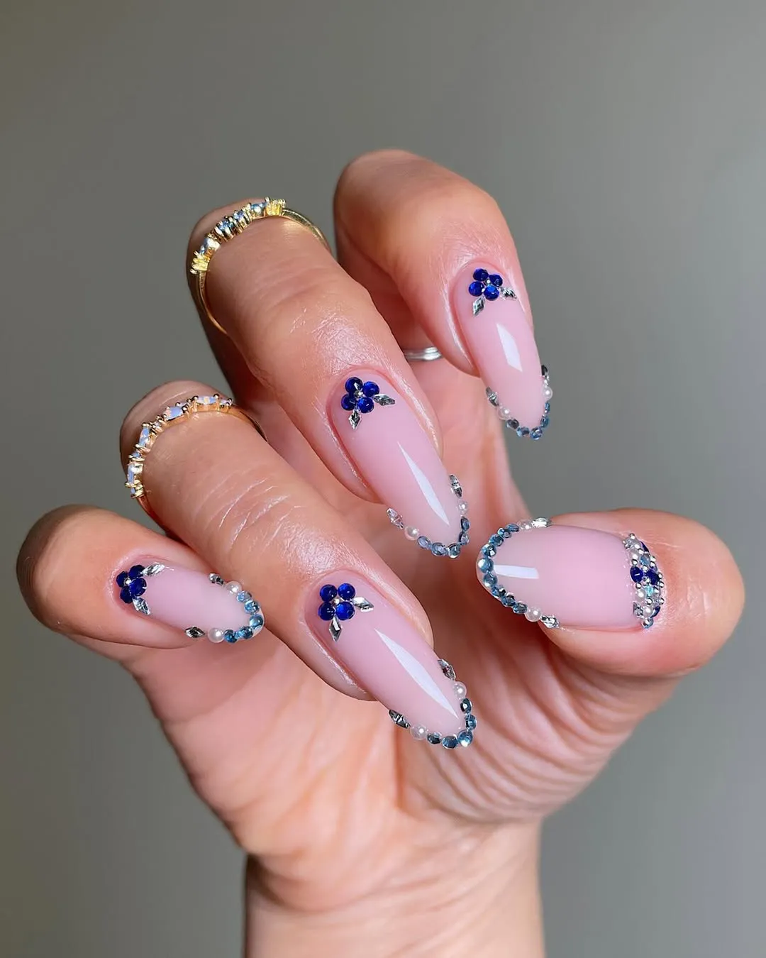 Hand with manicured nails featuring floral and gem accents