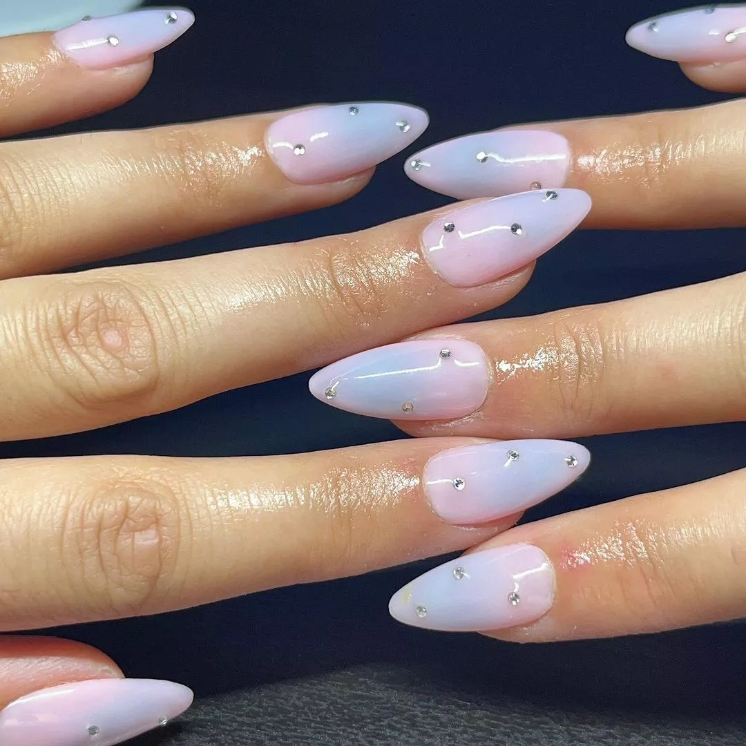 Person with medium-length cotton candy nails that have three silver gems on each nail