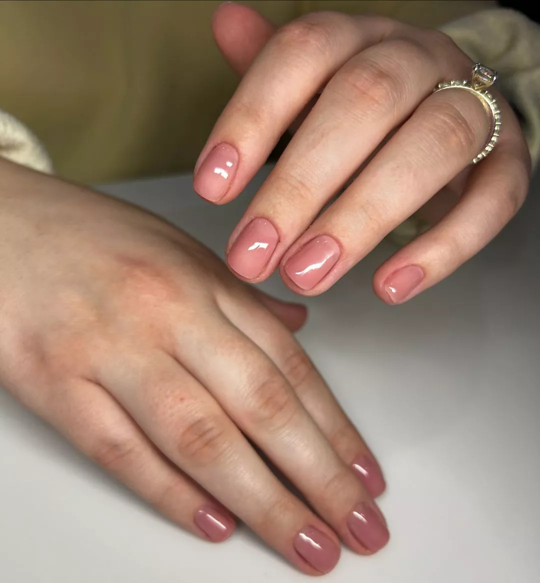 Person with short, squoval-shaped nails painted in a very light mauve