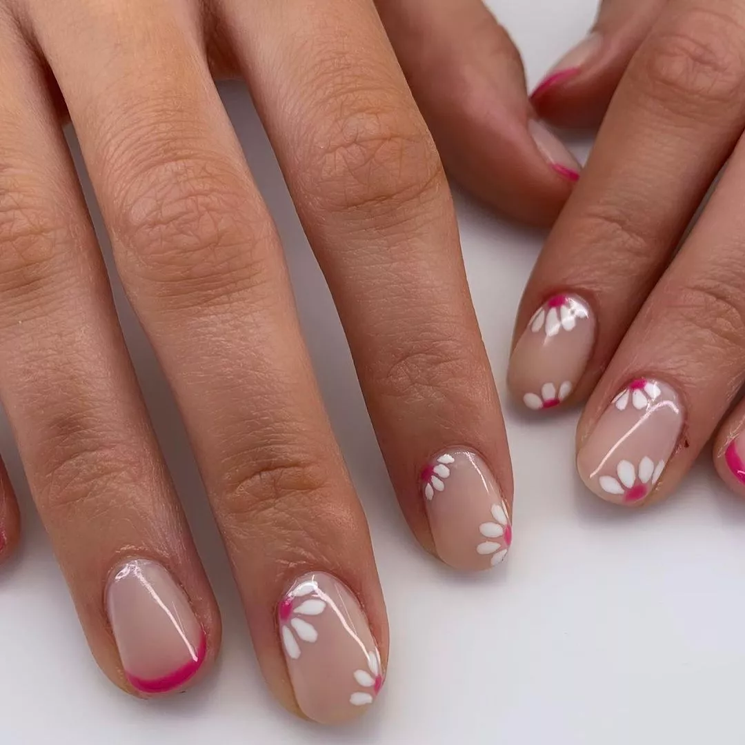 Person shows off their manicure, which alternates nails between daisies and hot pink French tips