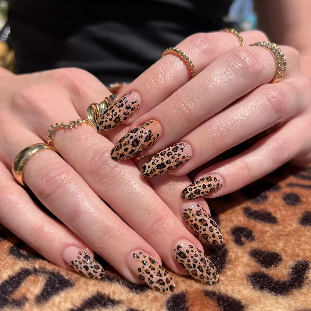 Person with long, oval-shaped nails that have a leopard print motif