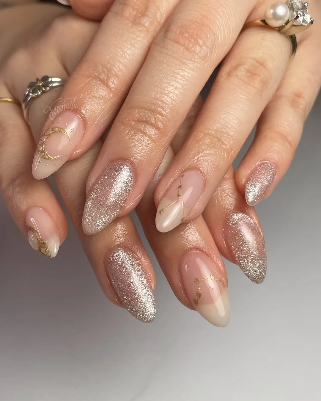 A nude manicure with gold constellations and champagne accent nails