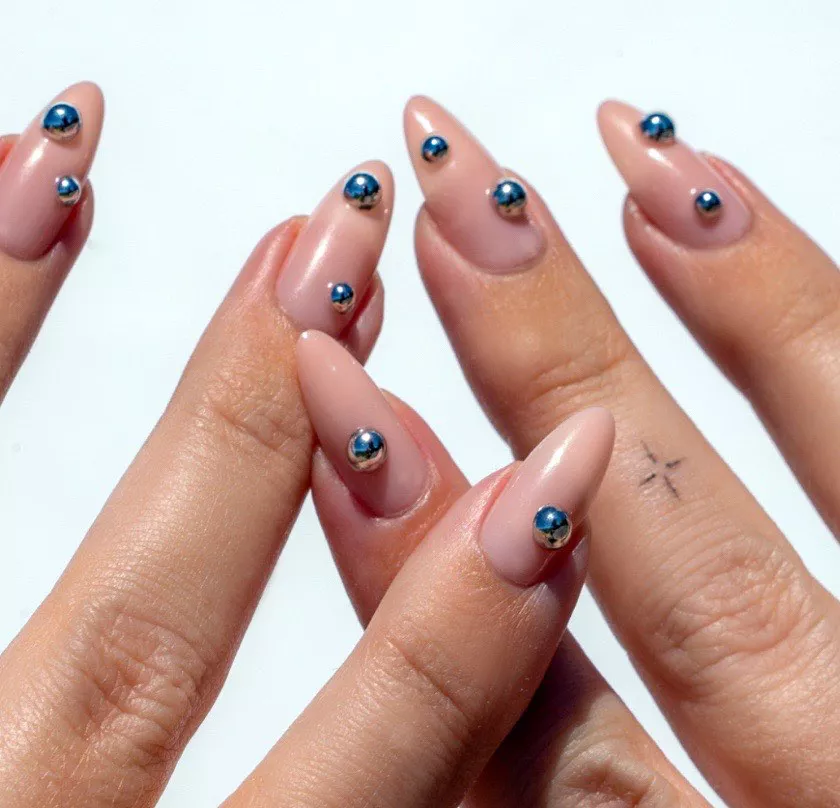 Person showing off their almond-shaped nails that have 3D silver spheres on each finger