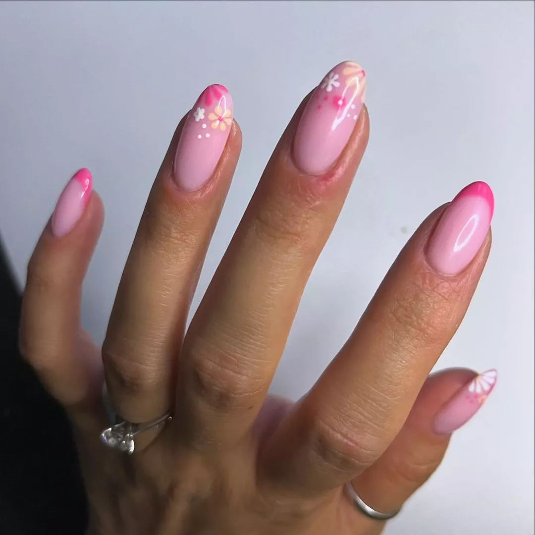 Person shows off their light pink nails, which have flowers and hot pink arcs on the tips