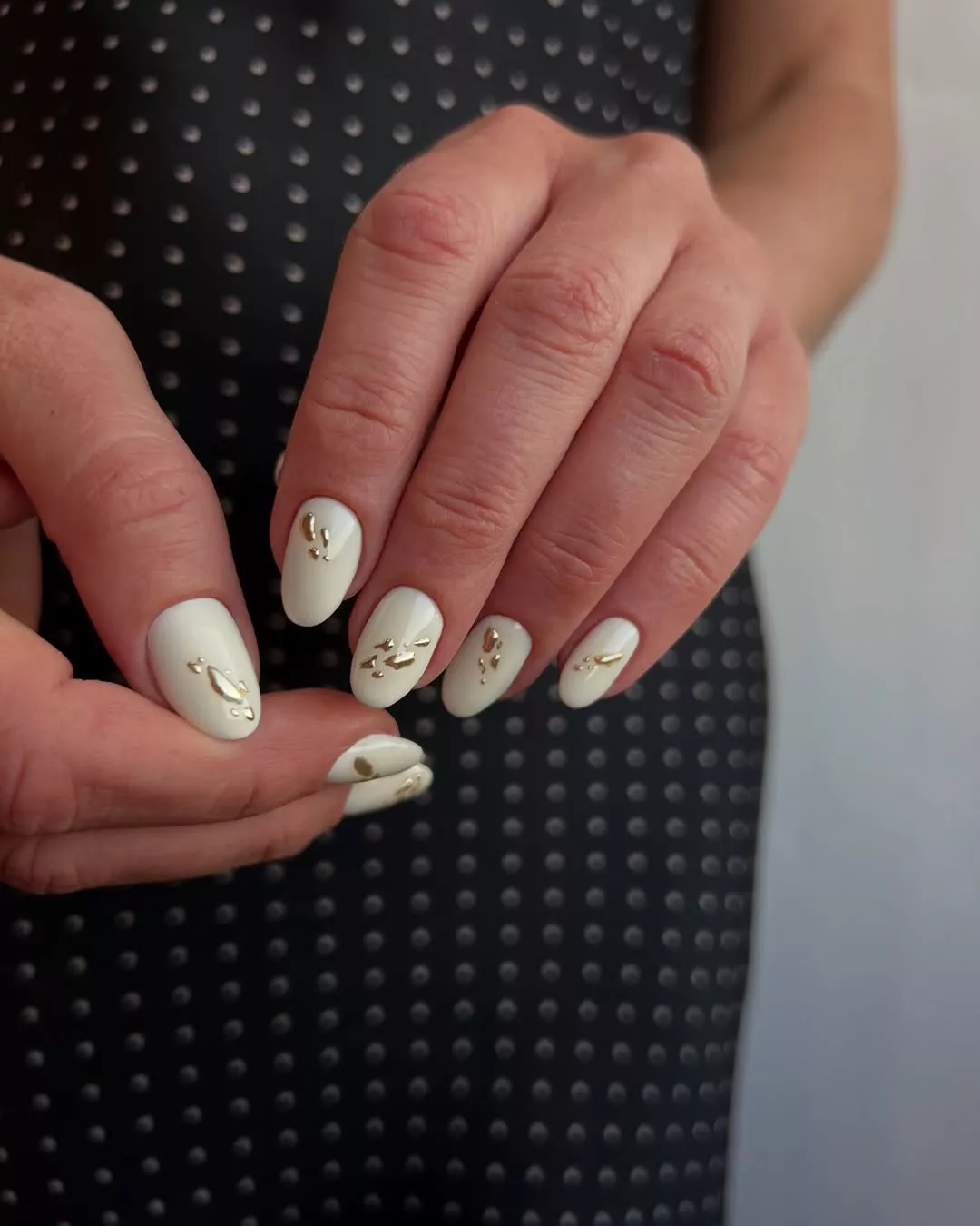 A cream manicure toped with 3D gold blobs.
