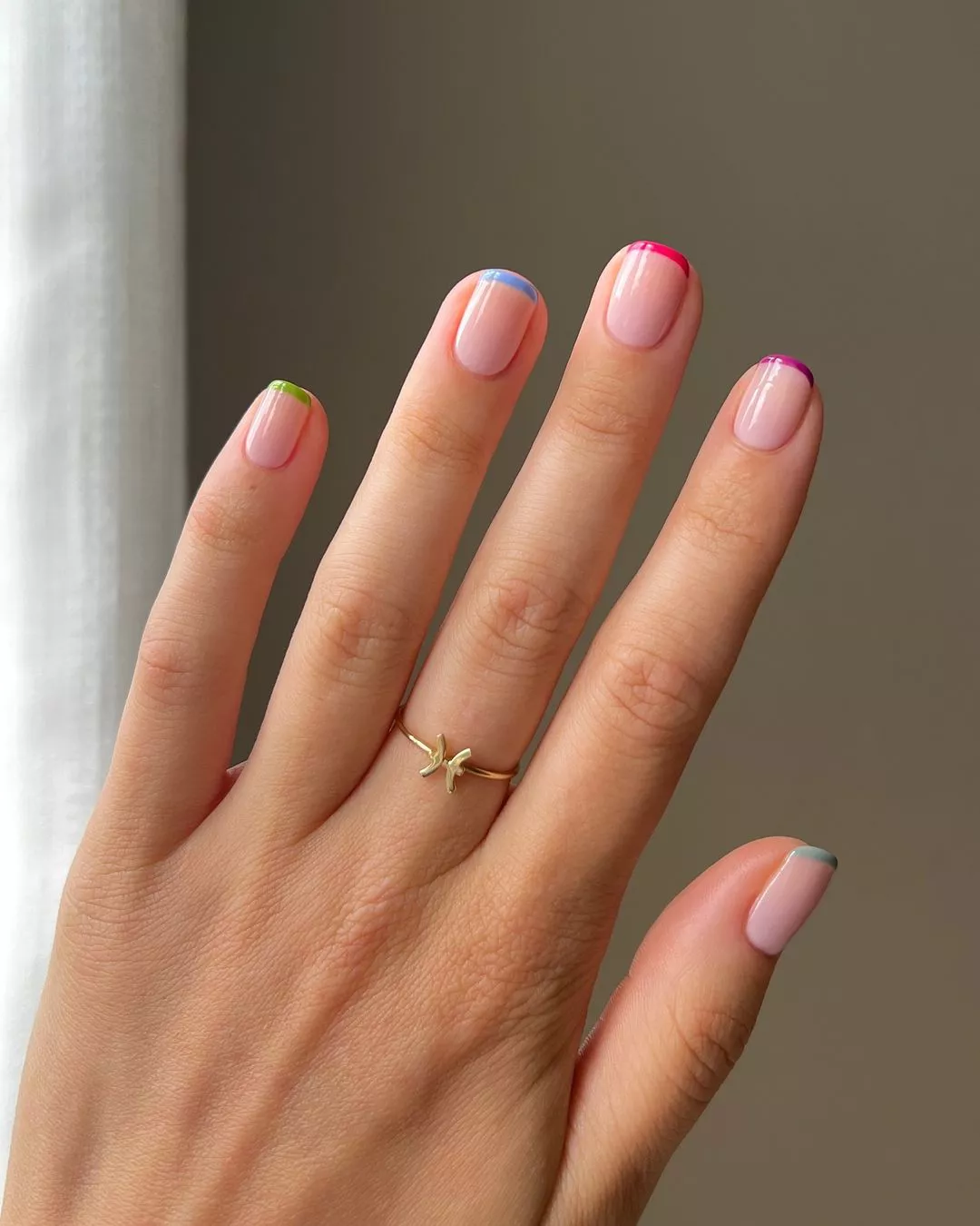 Person with short, squoval-shaped nails shows off their multi-colored micro French tip manicure