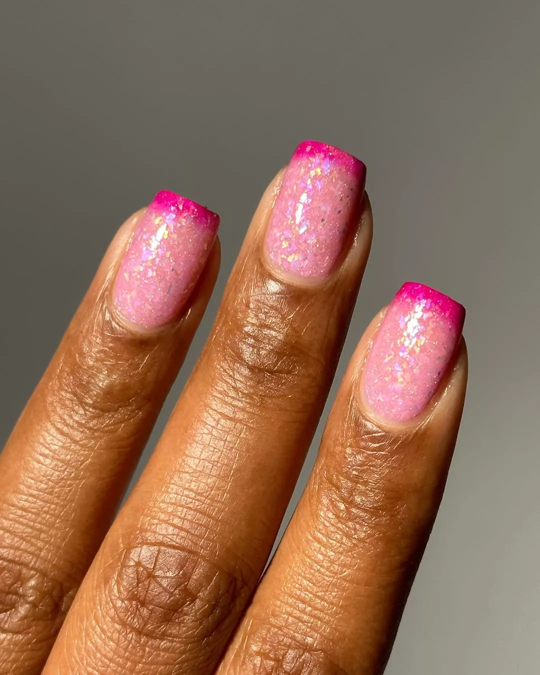 Person with hot pink French tips and a sparkly, light pink base