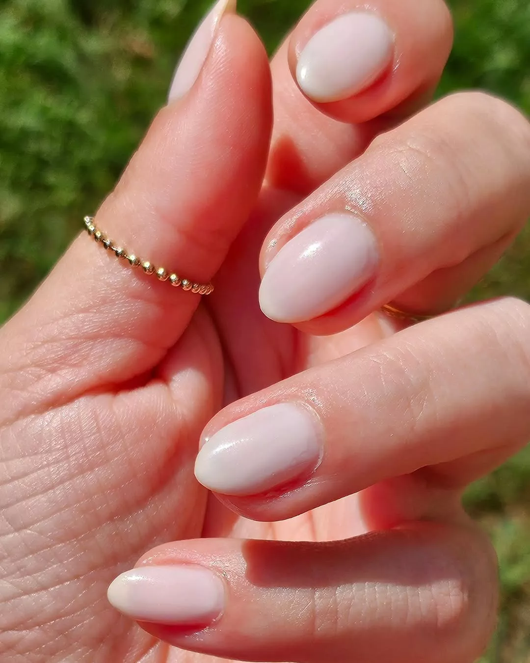 Person shows off their coffin-shaped nails, which are painted in a milky white polish