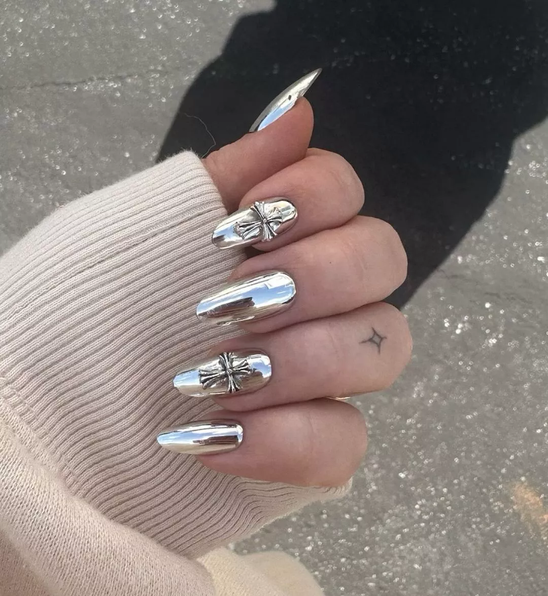 Person with medium-length oval nails featuring chrome designs on chrome polish