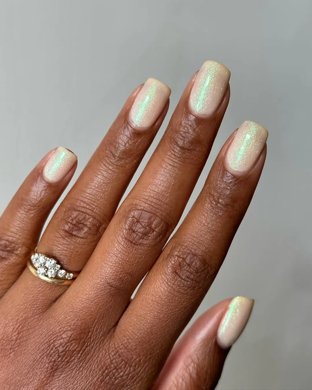 Square nails painted a holographic, glittery off-white shade