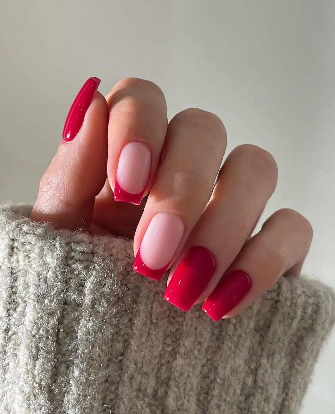 Manicured hand with a mix of pink and red polished nails