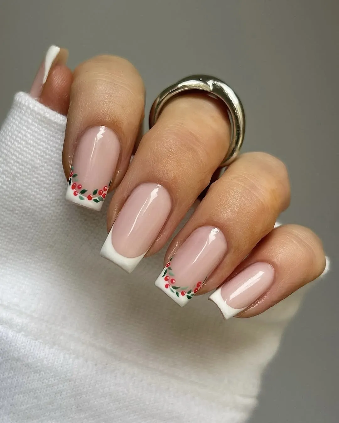 Classic French manicure with small holly art along two of the tips.