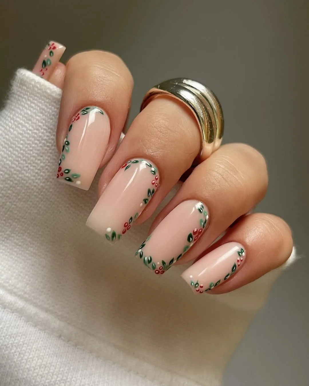 Neutral Christmas nails with a nude base and a border of berries and leaves.