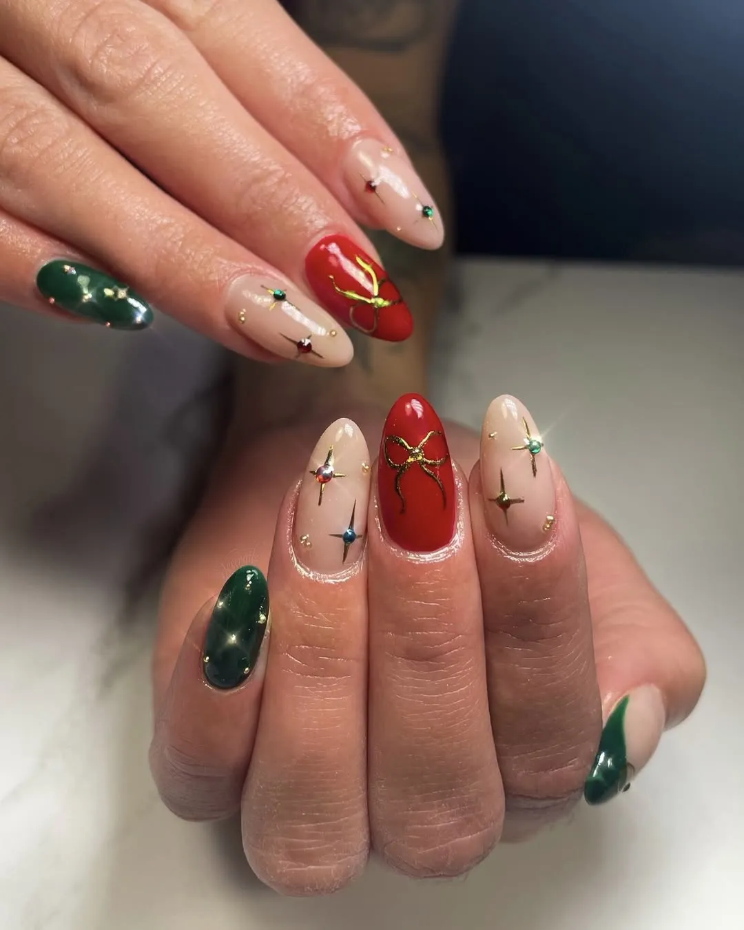 Red, green, and beige simple Christmas manicure with twinkle embellishments.