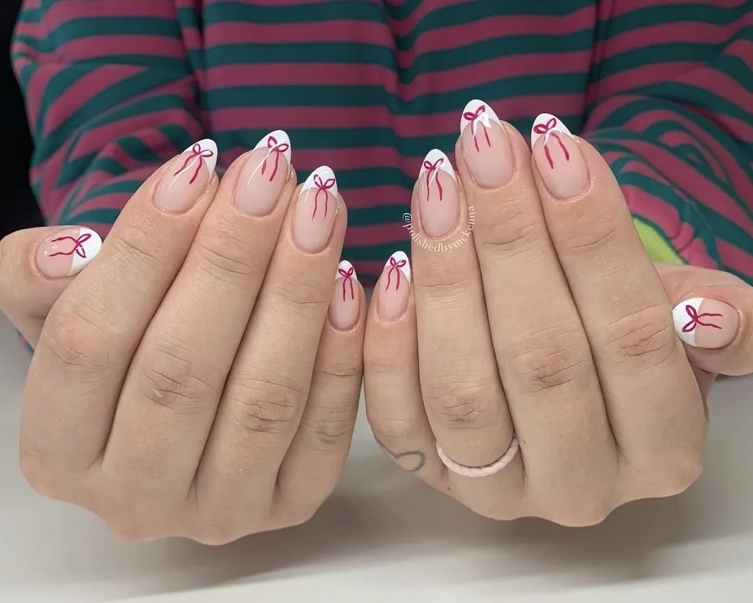 French manicure with red bow accents.