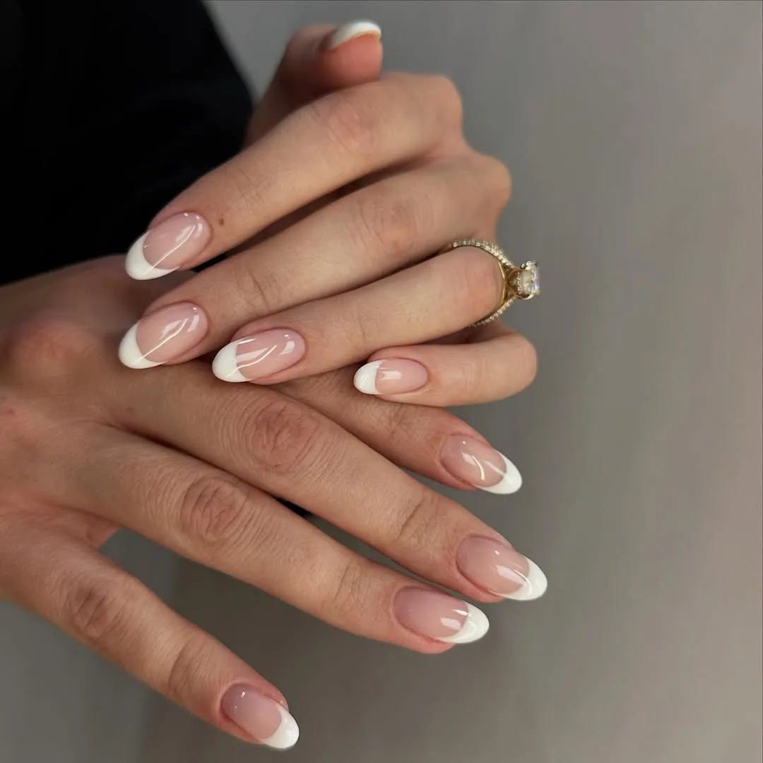 Hands with a ring wearing French manicured nails