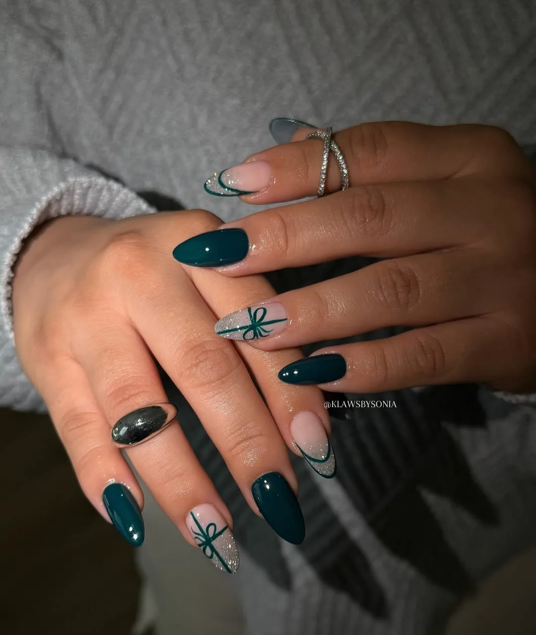 Manicured hands displaying glossy nail art with decorative patterns and rings on fingers