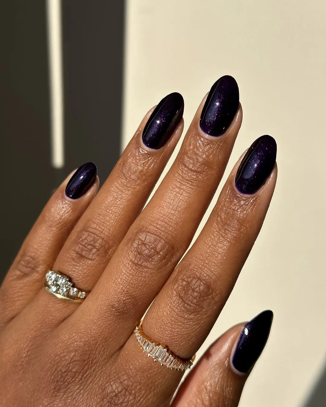 Person with a round, dark purple manicure that's similar to a galaxy