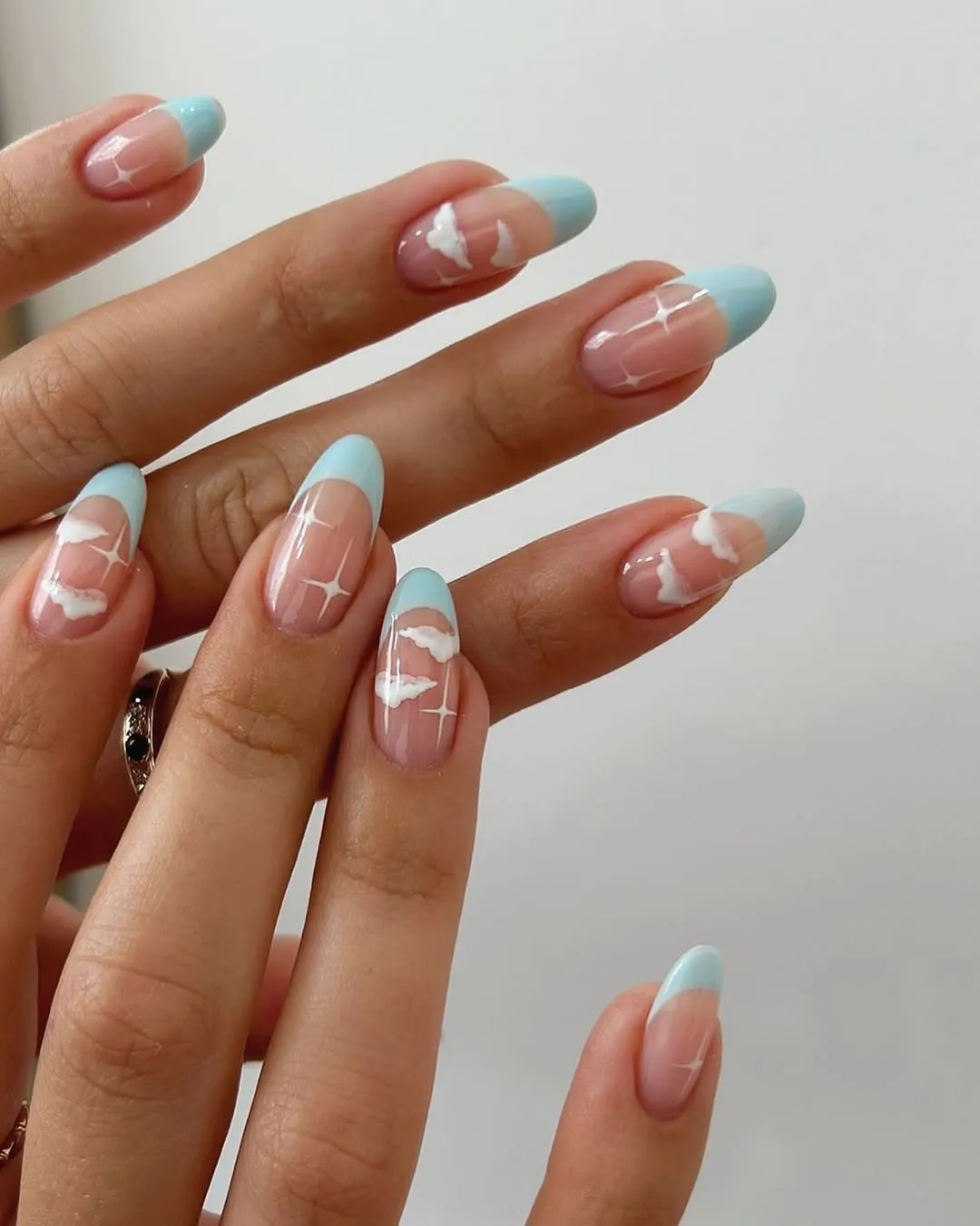 Closeup of hands with pastel blue and white nail art styled in an abstract design