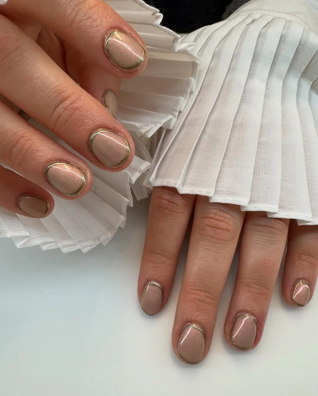 Short nails painted a champagne color with gold chrome outlines