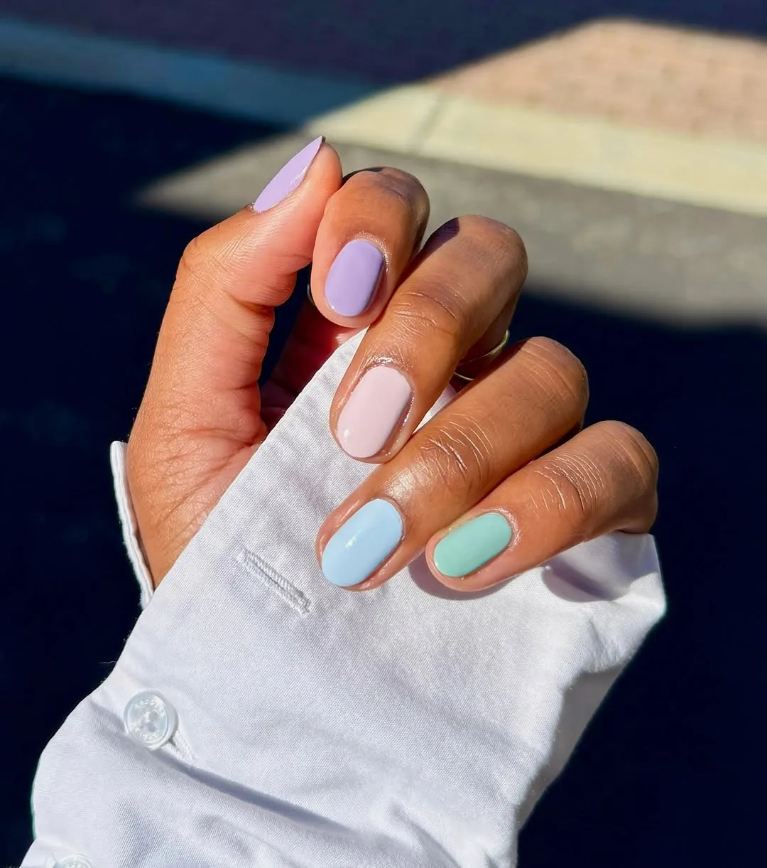 Person with a pastel gradient manicure featuring purple, peach, blue, and mint