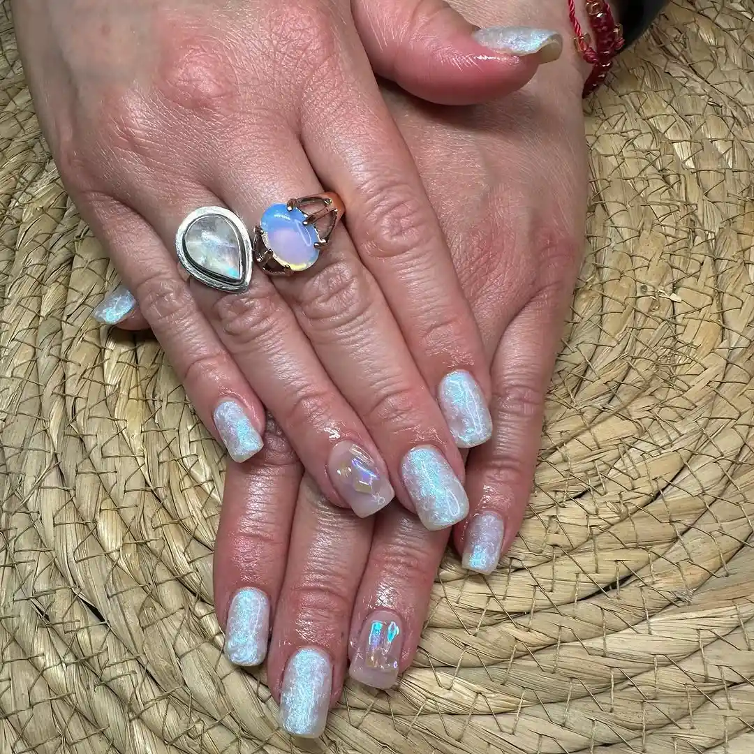 Person showing their medium-length blue chrome nails, which are iridescent and square shaped