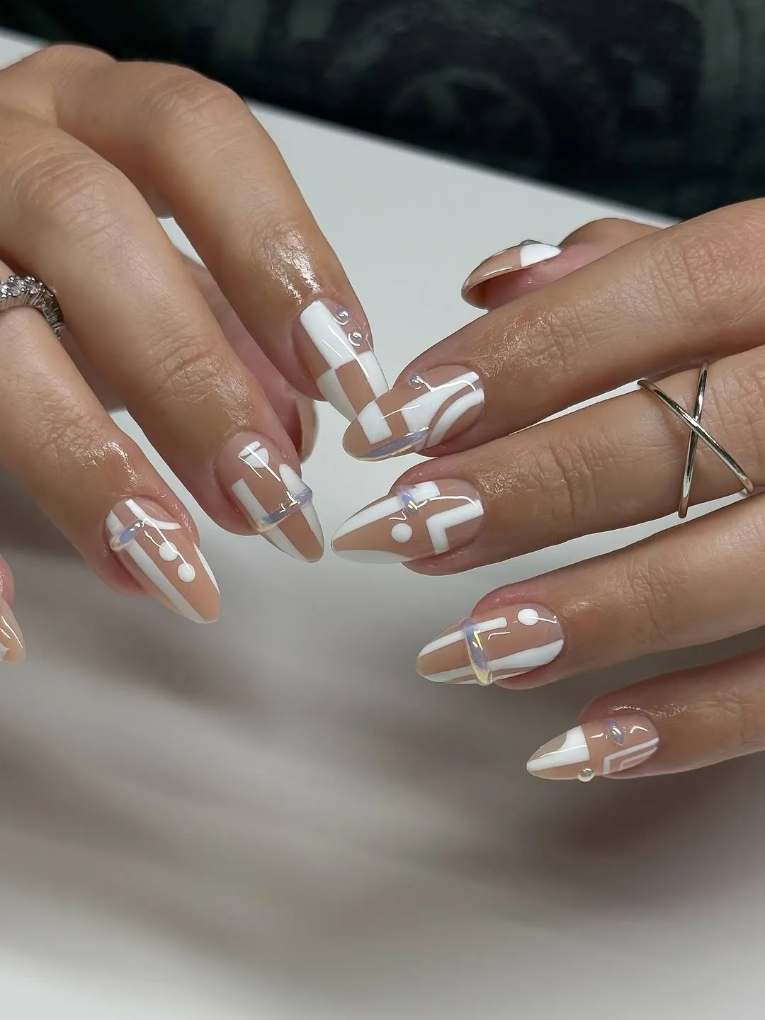 Hands with manicured nails featuring a geometric nail art design